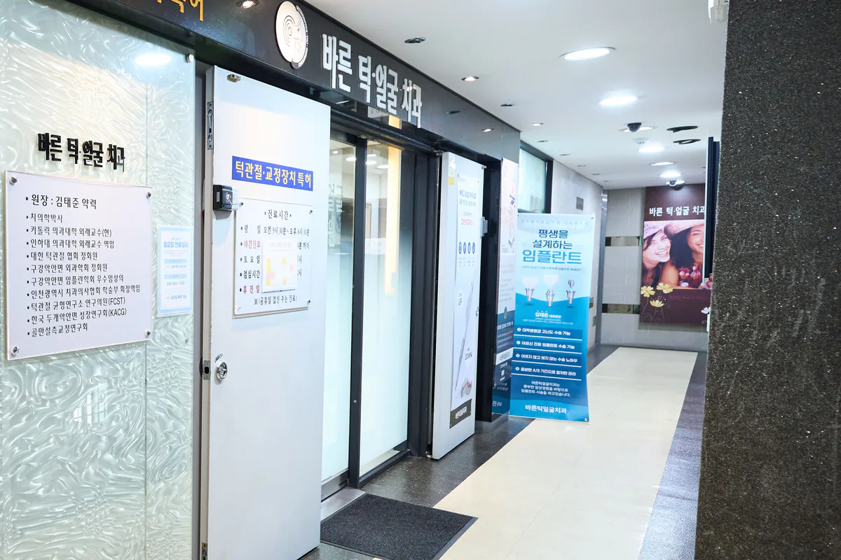 바른턱얼굴치과의원 4층 입구 복도 — 간판과 약력 명판, 출입문
