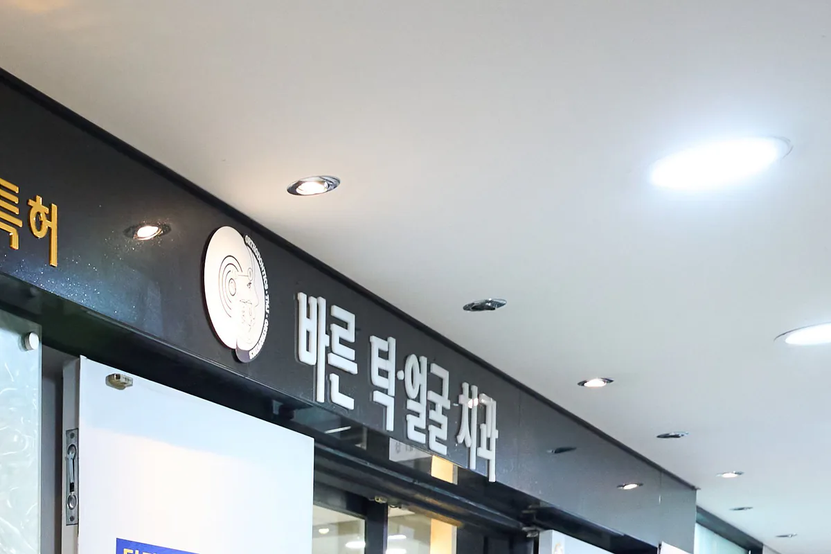 바른턱얼굴치과의원 4층 입구 사인 — 원형 엠블럼과 ‘바른 턱·얼굴 치과’ 간판