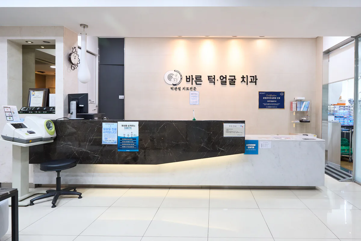 바른턱얼굴치과의원 안내데스크 로고월 — ‘바른 턱·얼굴 치과’ 사인과 접수 카운터